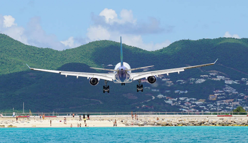   Samolot przelatujący nad ludźmi podczas lądowania na plaży Maho na Saint Maarten na lotnisku Princess Juliana.