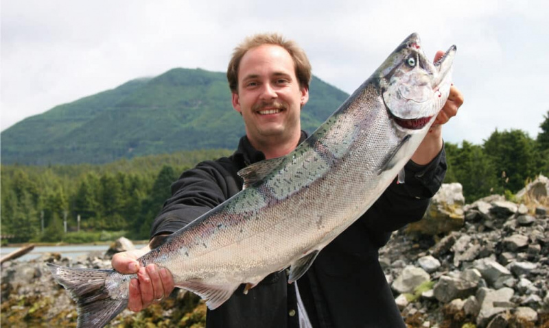   Um pescador com um salmão Chinook capturado no Canadá. Eles normalmente medem cerca de 3 metros de comprimento e 30 quilos de peso.