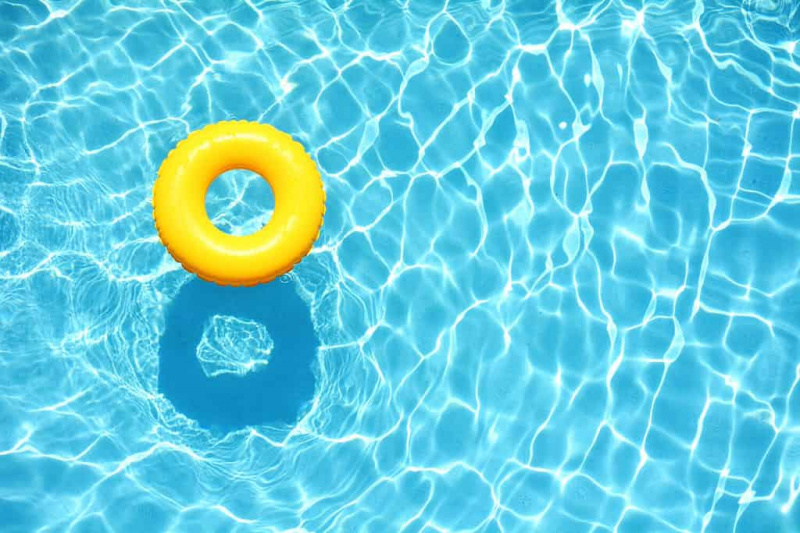 Flutuador de piscina amarela, anel flutuando em uma refrescante piscina azul
