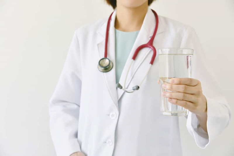   Zdravnik drži kozarec čiste sveže vode, zdravnik priporoča pitje zdrave vode.
